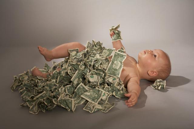 Baby wearing a blanket of dollar bills