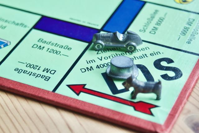 GO section of Monopoly game board with car, top hat and dog game pieces